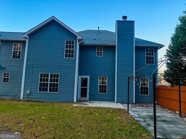 rear view of house featuring a patio area and a yard