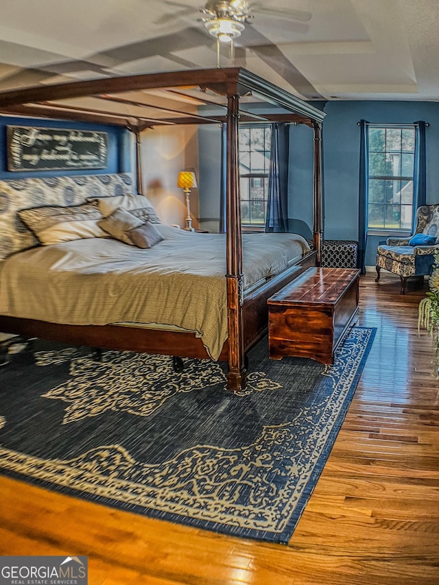 bedroom featuring a tray ceiling, ceiling fan, and wood-type flooring