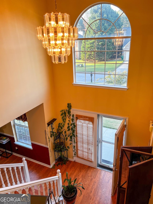 entryway with hardwood / wood-style floors, a chandelier, and a high ceiling