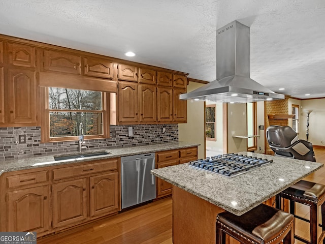 kitchen featuring island exhaust hood, a kitchen breakfast bar, stainless steel appliances, sink, and a center island