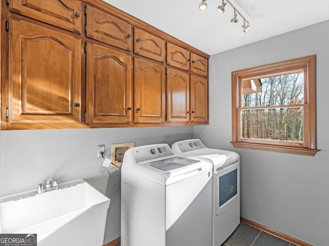 washroom with cabinets, washing machine and clothes dryer, and sink