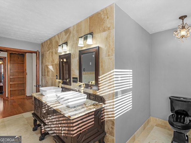 bathroom featuring tile patterned floors, vanity, tile walls, and a chandelier