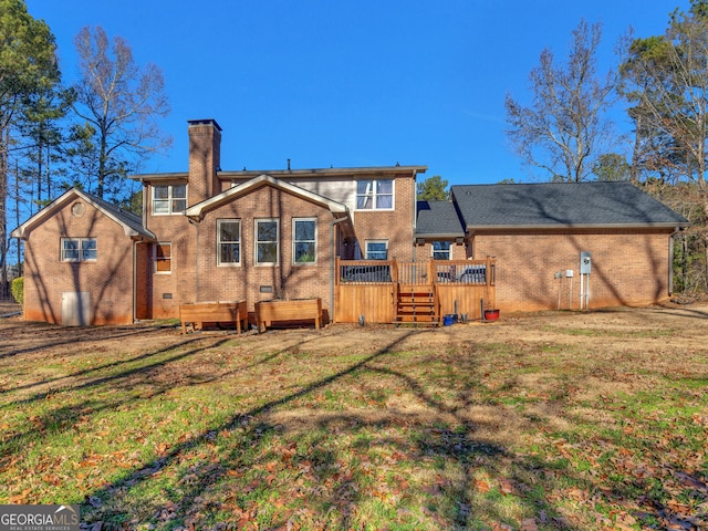 rear view of house featuring a lawn and a deck