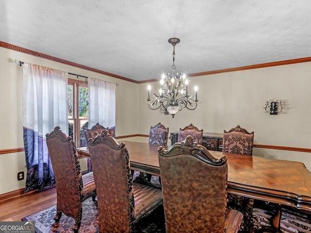 dining space with a textured ceiling, hardwood / wood-style flooring, an inviting chandelier, and crown molding