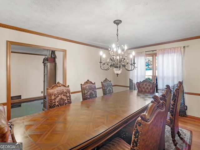 dining room with hardwood / wood-style floors, a notable chandelier, crown molding, and a textured ceiling