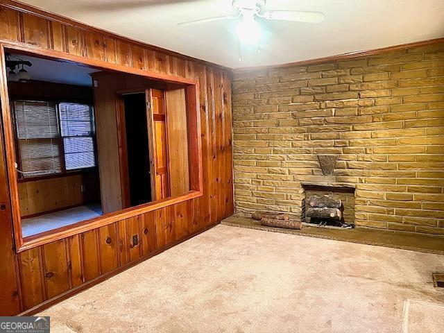 unfurnished living room with carpet flooring, ceiling fan, and wooden walls