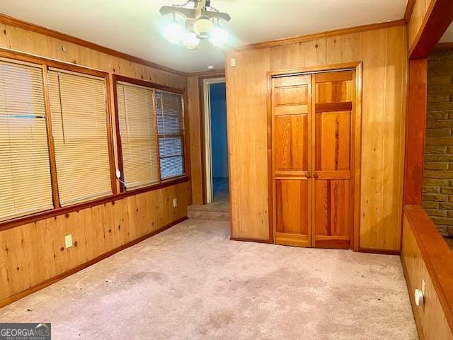 spare room with wooden walls, light colored carpet, and ornamental molding