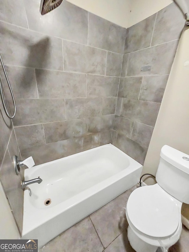 bathroom with tile patterned flooring, tiled shower / bath combo, and toilet