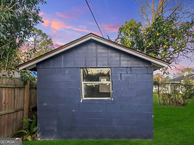 property exterior at dusk featuring a yard and an outdoor structure