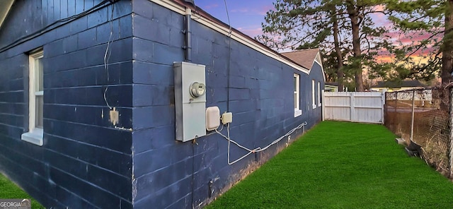 property exterior at dusk featuring a lawn