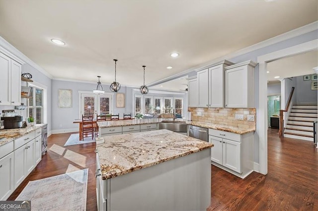 kitchen with kitchen peninsula, a center island, white cabinets, and hanging light fixtures