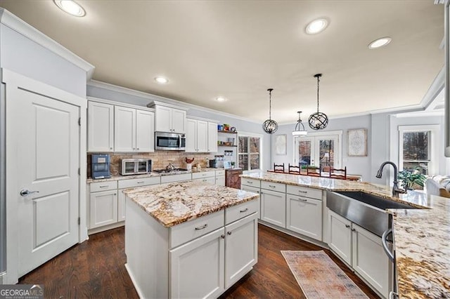 kitchen featuring white cabinets, sink, hanging light fixtures, light stone countertops, and stainless steel appliances