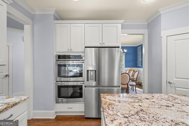 kitchen featuring white cabinets, light stone countertops, stainless steel appliances, and ornamental molding