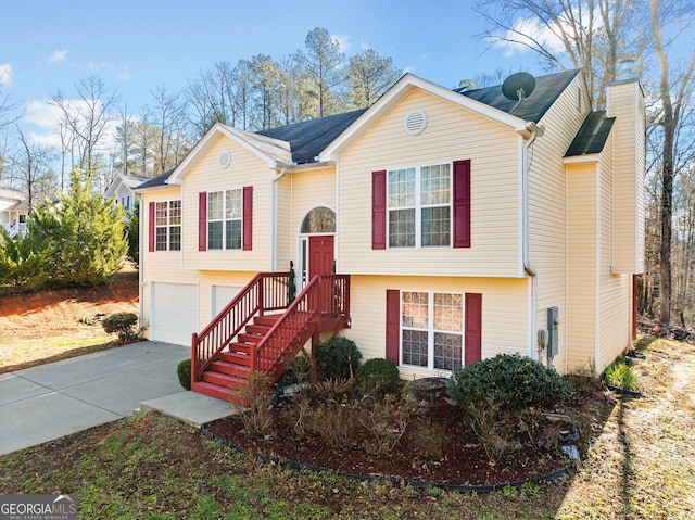 bi-level home with a garage, concrete driveway, and a chimney