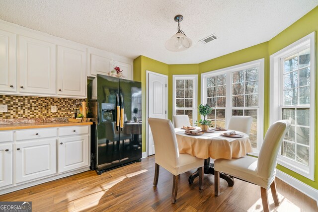 dining space with a textured ceiling and light wood-type flooring