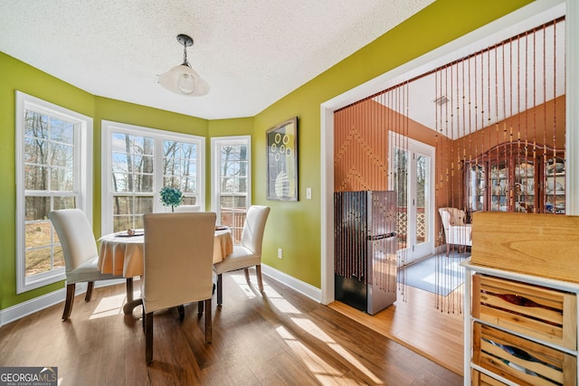 dining space featuring wood-type flooring and a textured ceiling