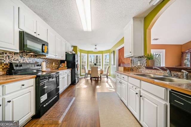 kitchen featuring decorative backsplash, sink, white cabinets, and black appliances