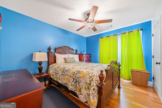 bedroom featuring ceiling fan, light hardwood / wood-style floors, and a textured ceiling