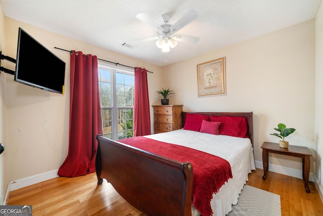 bedroom featuring a textured ceiling, light wood-type flooring, and ceiling fan