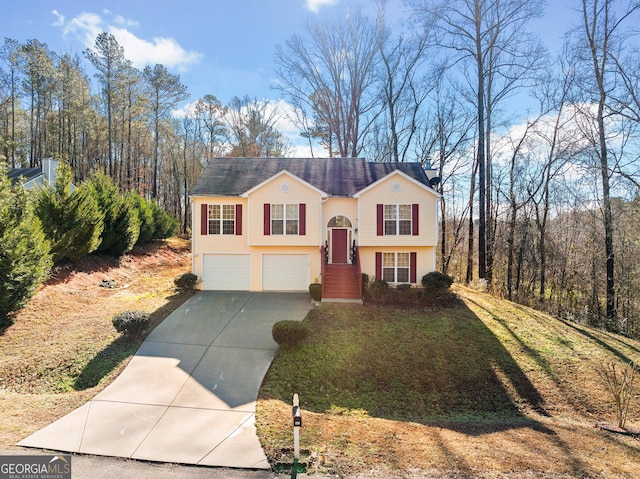 split foyer home with concrete driveway, an attached garage, and a front yard