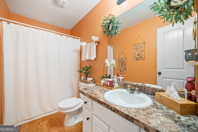 bathroom featuring vanity, wood-type flooring, a textured ceiling, and toilet