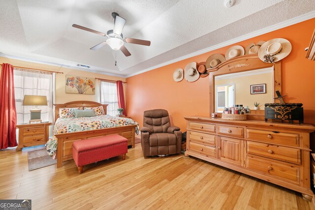 bedroom with a tray ceiling, light hardwood / wood-style flooring, ceiling fan, and ornamental molding