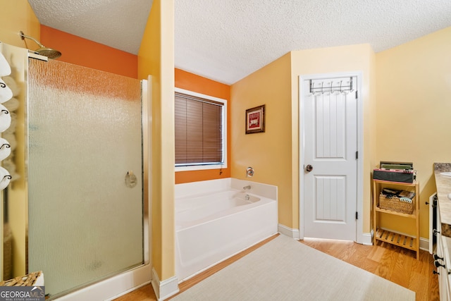 bathroom featuring hardwood / wood-style floors, independent shower and bath, and a textured ceiling