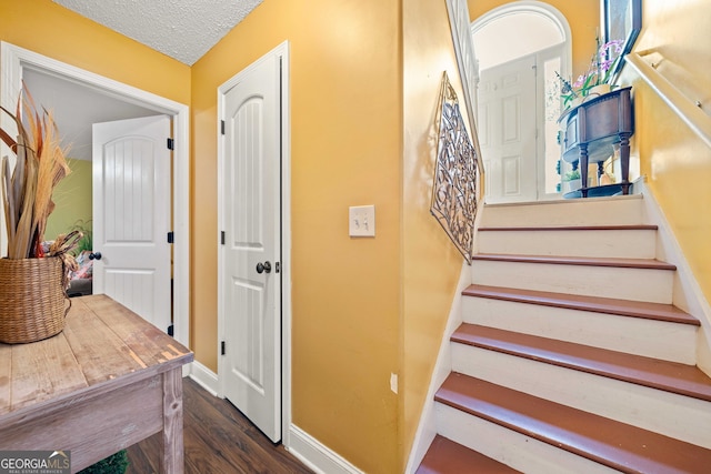 stairway with wood-type flooring and a textured ceiling