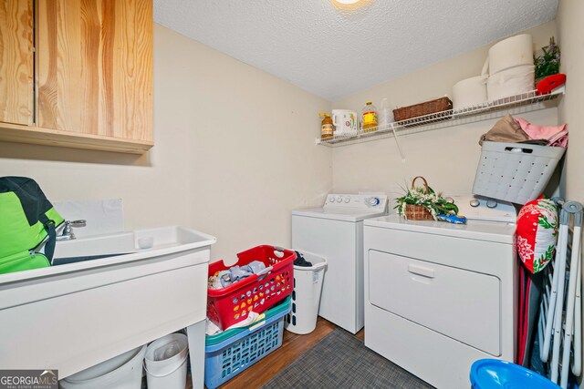 laundry area featuring cabinets, dark hardwood / wood-style flooring, washing machine and dryer, and a textured ceiling