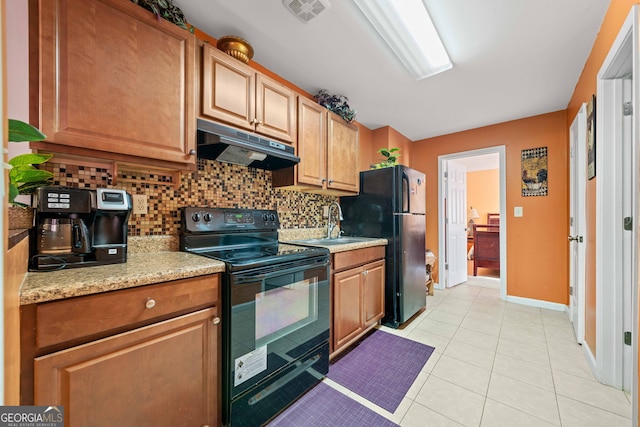 kitchen featuring light tile patterned flooring, backsplash, light stone counters, and black appliances