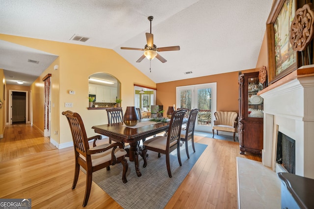 dining area with a textured ceiling, ceiling fan, lofted ceiling, and light wood-type flooring