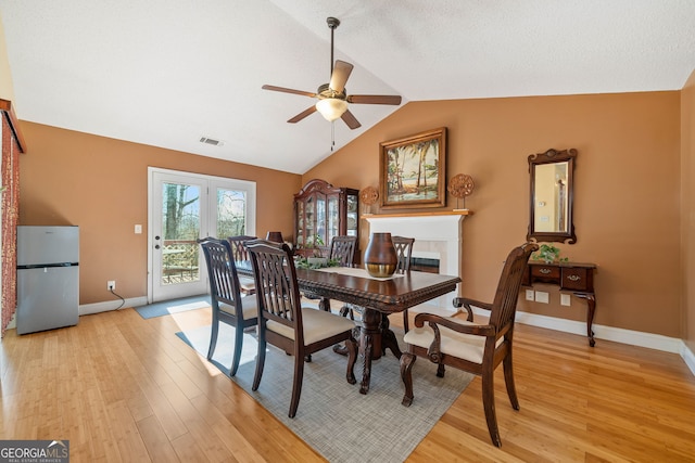 dining area with ceiling fan, light hardwood / wood-style floors, and vaulted ceiling