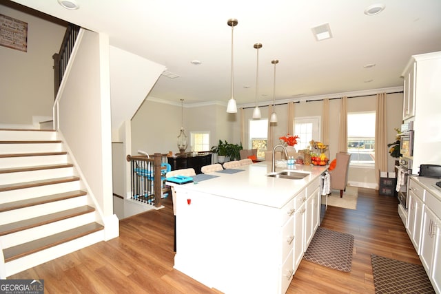 kitchen with pendant lighting, white cabinets, sink, and an island with sink