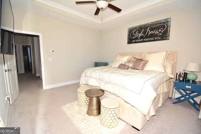 bedroom with light carpet, a tray ceiling, ceiling fan, and ornamental molding