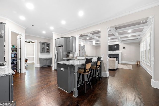 kitchen featuring a kitchen bar, dark hardwood / wood-style flooring, coffered ceiling, beam ceiling, and gray cabinets