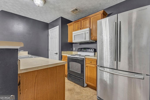 kitchen featuring freestanding refrigerator, range with electric cooktop, white microwave, a sink, and light countertops