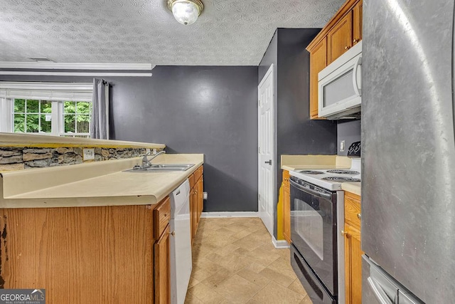 kitchen with white appliances, a sink, light countertops, baseboards, and brown cabinets