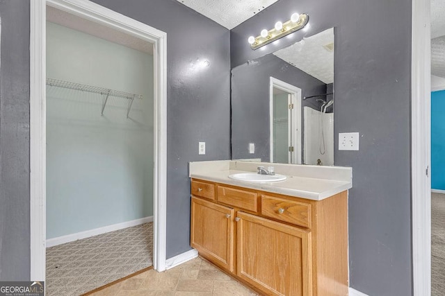 full bathroom with vanity, baseboards, and a spacious closet