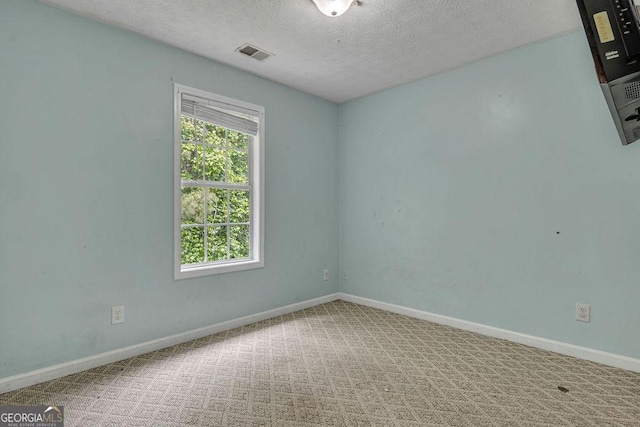 empty room featuring a textured ceiling, carpet, and baseboards