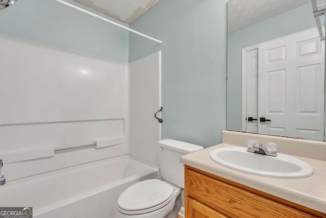 bathroom with a textured ceiling, toilet, vanity, and tub / shower combination