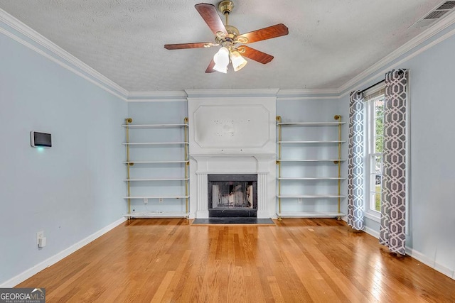 unfurnished living room with light wood-type flooring, a fireplace, ceiling fan, baseboards, and ornamental molding
