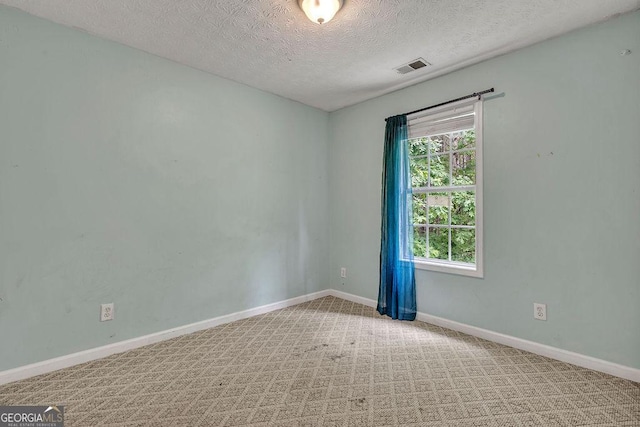 spare room with a textured ceiling, baseboards, and carpet