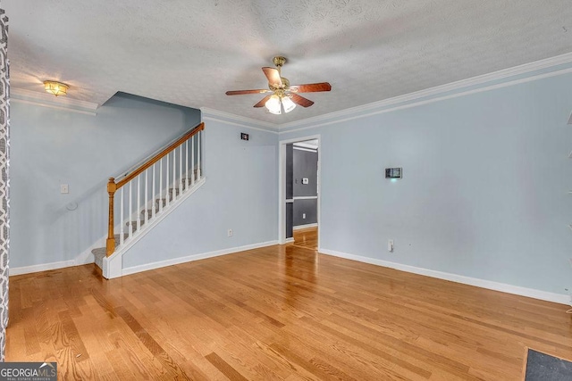 unfurnished living room featuring ceiling fan, stairs, light wood finished floors, crown molding, and a textured ceiling