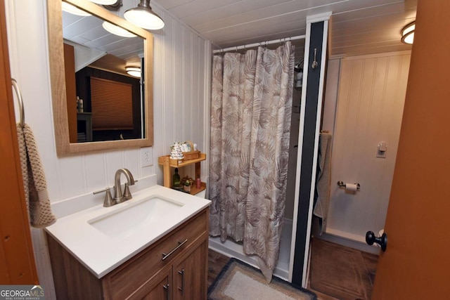 bathroom featuring a shower with shower curtain, vanity, and wood walls