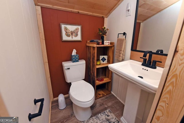 bathroom with hardwood / wood-style flooring, wood walls, and toilet