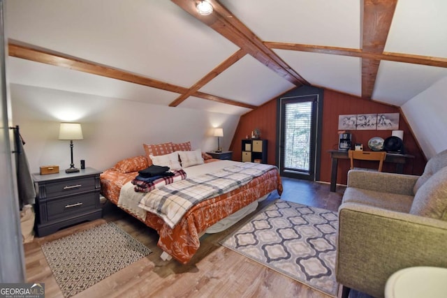 bedroom featuring hardwood / wood-style floors, vaulted ceiling, and wooden walls