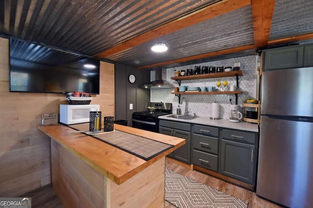 kitchen featuring appliances with stainless steel finishes, tasteful backsplash, gray cabinetry, wall chimney exhaust hood, and sink