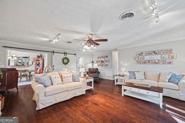 living room featuring a barn door, ceiling fan, crown molding, and dark wood-type flooring