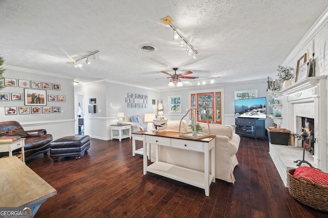 living room with dark hardwood / wood-style flooring, track lighting, and crown molding