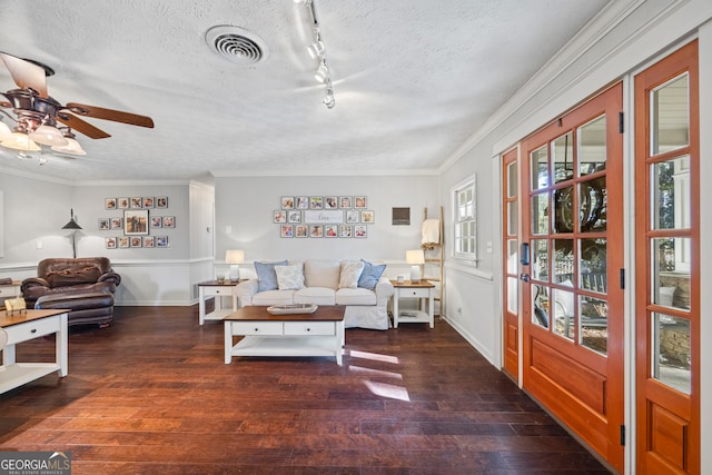 living room featuring a textured ceiling, crown molding, dark wood-type flooring, and track lighting